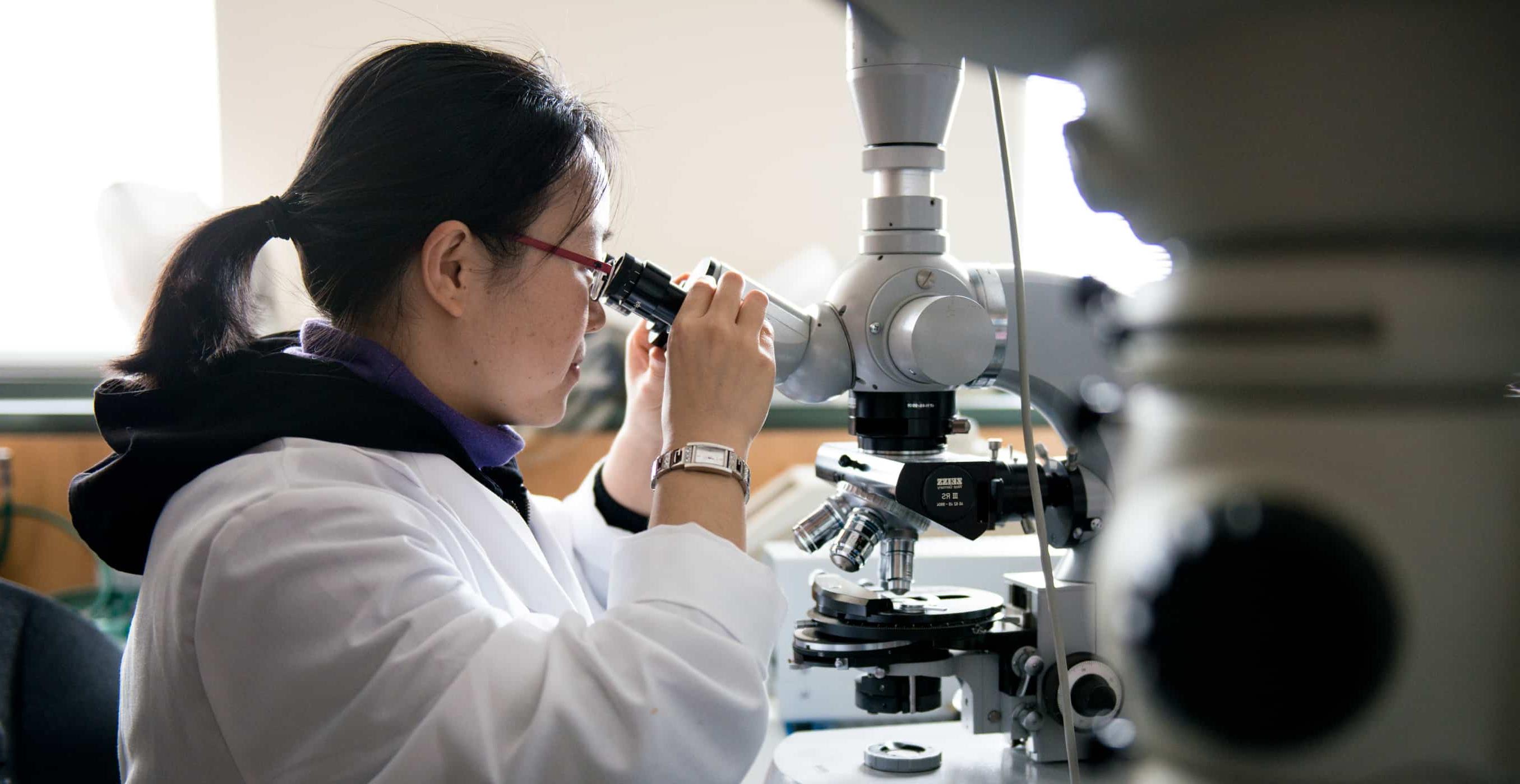 Student looking into microscope in Biology lab