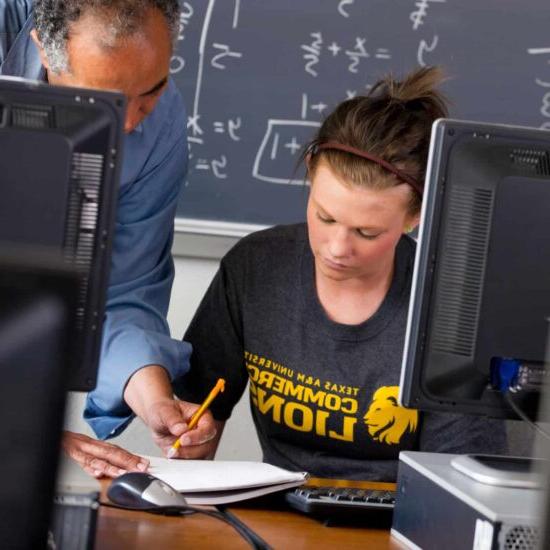 A professor helping a female student with an assignment.