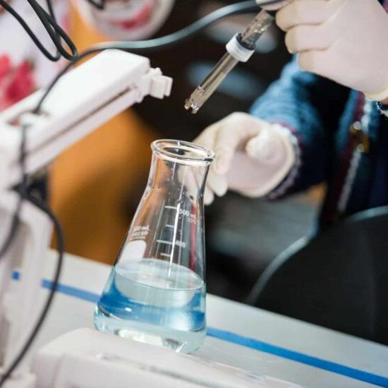 Someone pouring chemical products into a vial.