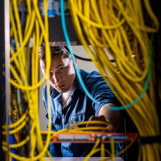 A male student looking in a system filled with electric wires.