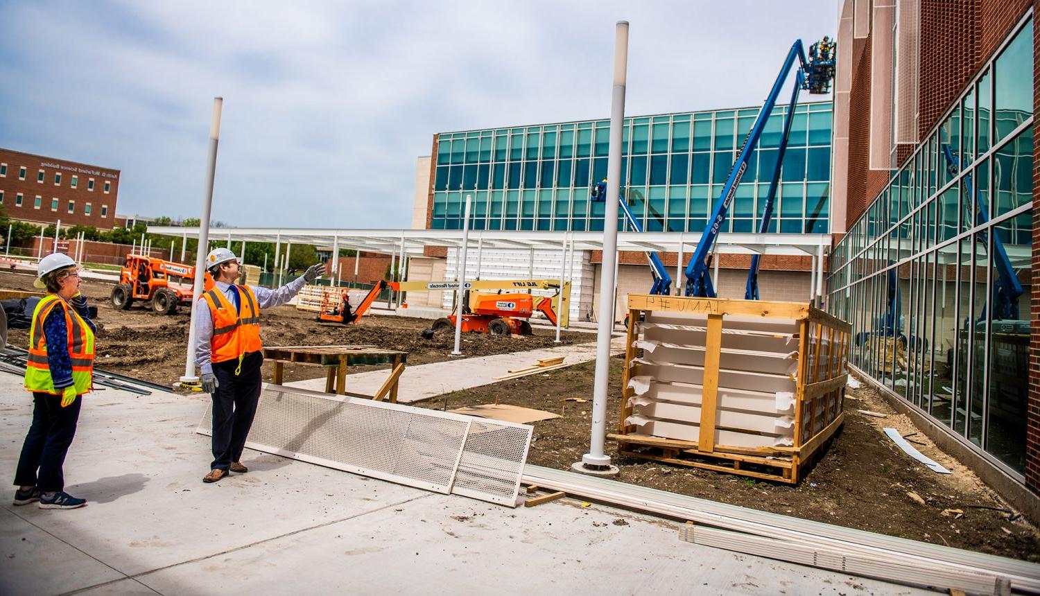 Construction workers discussing the project they are working on. While other workers are working in the background.