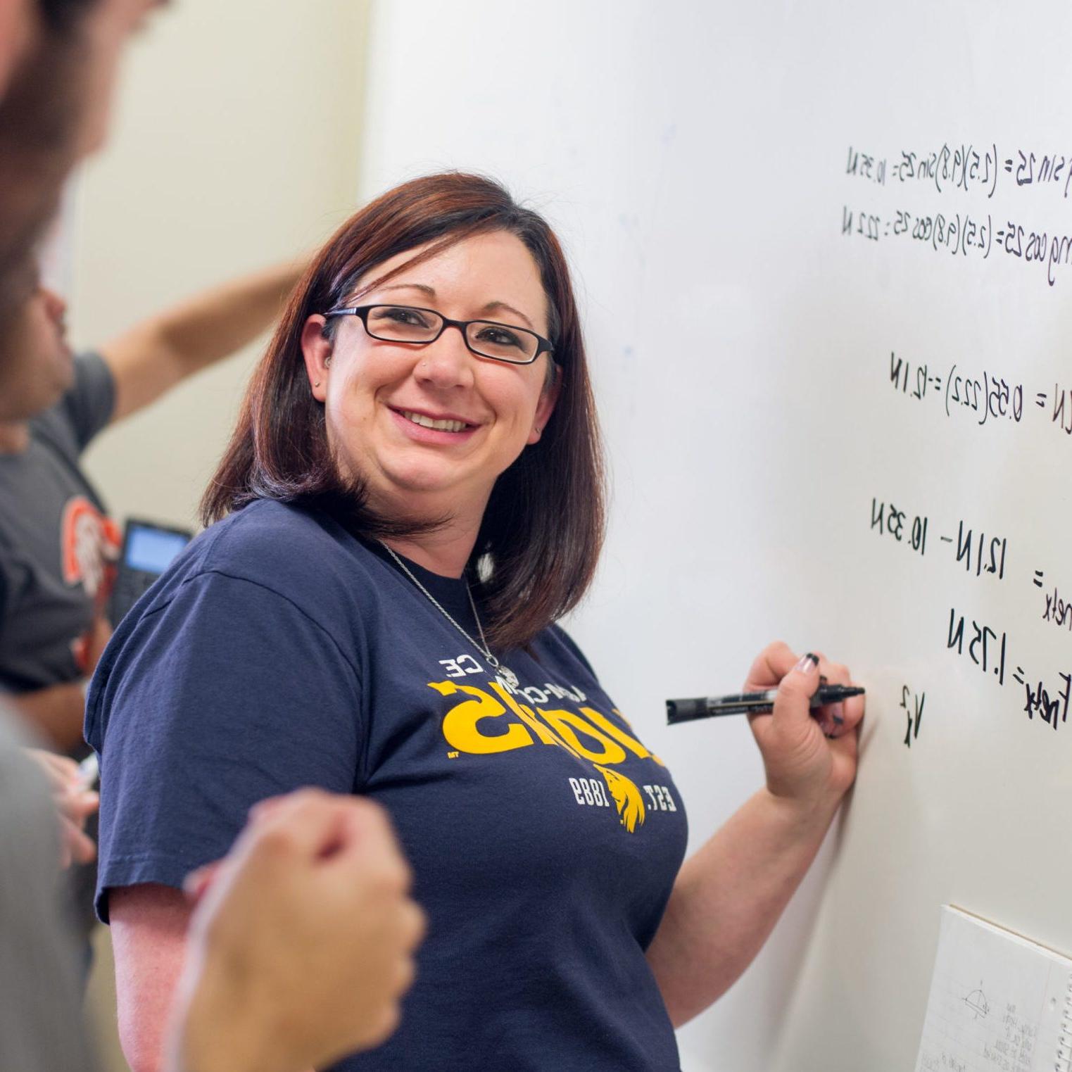 Woman solving a problem on a board.