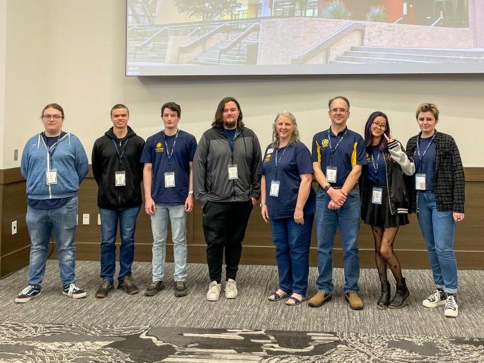 A group of students and faculty stand side by side for a photo.